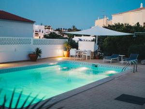a swimming pool with a table and chairs and an umbrella at Vivenda Brito in Carvoeiro