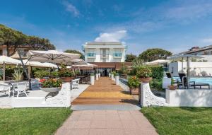 een loopbrug met stoelen en parasols naast een zwembad bij Park Hotel Ermitage Resort & Spa in Lido di Jesolo