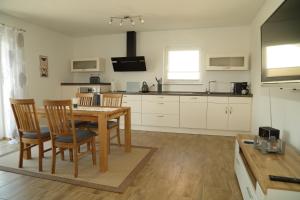 a kitchen with a wooden table and chairs and a dining room at Riethelblick in Volkesfeld