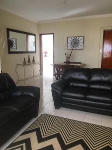 a living room with a black leather couch and a rug at apto de frente ao mar in Praia Grande