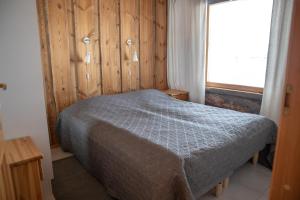1 dormitorio con 1 cama con pared de madera en Lost Inn Cabins, en Äkäslompolo