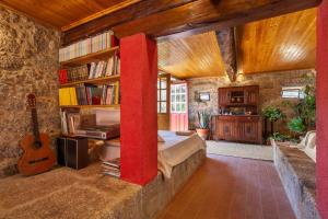 een slaapkamer met een bed en een gitaar in een kamer bij Casa do Eido - sustainable living & nature experiences Gerês in Geres