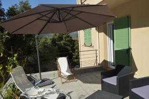 eine Terrasse mit einem Sonnenschirm und Stühlen auf einem Balkon in der Unterkunft La Villa Volpaso in Belgodère