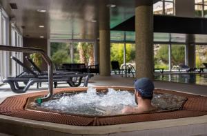 Ein Mann in einem Whirlpool in einem Gebäude in der Unterkunft Puralã - Wool Valley Hotel & SPA in Covilhã