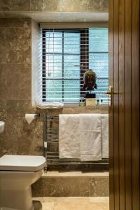La salle de bains est pourvue de toilettes, d'une fenêtre et de serviettes. dans l'établissement The Mews Hotel, à Wakefield