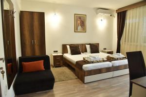 a hotel room with two beds and a chair at Apartmani Centar Kumanovo in Kumanovo