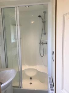 a white bathroom with a shower and a sink at Countryside views from a luxury mobile home near Perranporth in Perranporth