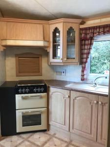 a kitchen with wooden cabinets and a stove top oven at Countryside views from a luxury mobile home near Perranporth in Perranporth