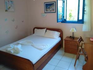 a bedroom with a bed with white sheets and a table at Mouragio Studios in Tyros