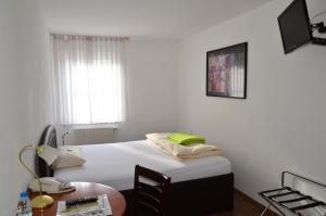 a bedroom with a bed with a table and a window at Hotel Mörike in Ludwigsburg