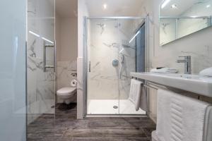 ein Bad mit einer Dusche, einem Waschbecken und einem WC in der Unterkunft Hotel Monarc in Ostende