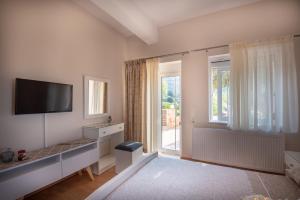 biały salon z telewizorem i oknem w obiekcie Panorama Country Residence w mieście Tzitzifés
