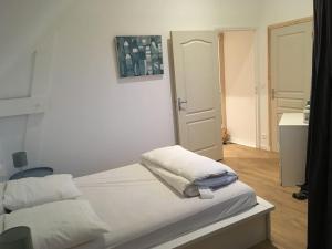 a bedroom with a bed with white sheets and a door at Gite Bord de Mer 80 m2 in Bernières-sur-Mer