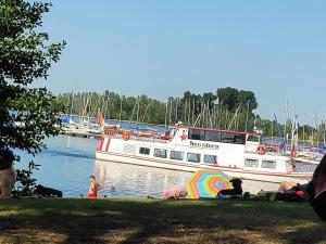 Una barca in acqua con persone sedute sull'erba di Inseldorf Wardt a Xanten