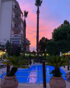 un hotel con palmeras y una piscina al atardecer en Hotel La Rotonda, en Cepagatti