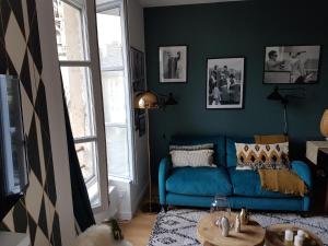 ein Wohnzimmer mit einem blauen Sofa und einem Tisch in der Unterkunft Fiquet de Normanville pour votre bien être en plein coeur historique in Rouen