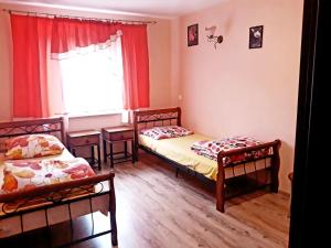 a bedroom with two beds and a window with red curtains at Gospodarstwo Agroturystyczne Pod Lasem Maria Płazio in Narol