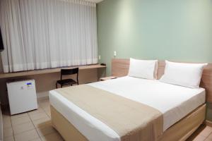 um quarto com uma cama grande e uma cadeira em Hotel Vila Leste em Teresina