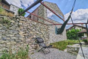 a hammock in front of a stone wall at Renovated historic barn in mountain village in Ollon