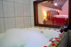 a bath tub in a room with a mirror at Chalés Fazenda Vale da Mata in Monte Verde