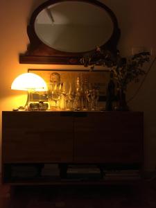 a lamp sitting on top of a dresser with a mirror at Bom Retiro, literature & coffee in Sao Paulo