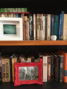 a book shelf with a red picture frame on it at Bom Retiro, literature & coffee in São Paulo