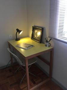 einen Schreibtisch mit einer Lampe und einem Bild darauf in der Unterkunft Bom Retiro, literature & coffee in São Paulo