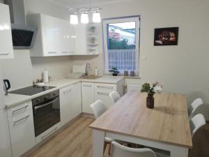 a kitchen with a wooden table and white cabinets at Apartamet Marzenie 7 - Opole in Opole