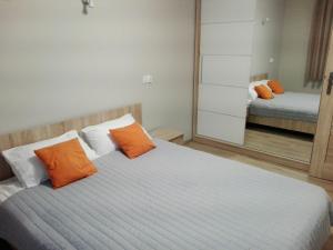1 dormitorio con 1 cama con almohadas de color naranja y espejo en Apartamet Marzenie 7 - Opole, en Opole