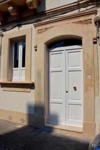 eine weiße Tür und zwei Fenster auf einem Gebäude in der Unterkunft Casa Euribia in Augusta