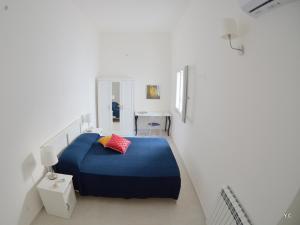 ein Schlafzimmer mit einem blauen Bett in einem weißen Zimmer in der Unterkunft Casa Euribia in Augusta