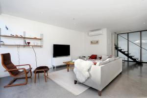 a living room with a couch and chairs and a tv at StayCentral - Collingwood Penthouse on Oxford in Melbourne
