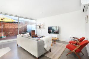 a living room with a couch and a tv at StayCentral - Collingwood Penthouse on Oxford in Melbourne