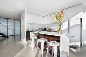 a kitchen with white walls and a counter with stools at StayCentral - Collingwood Penthouse on Oxford in Melbourne