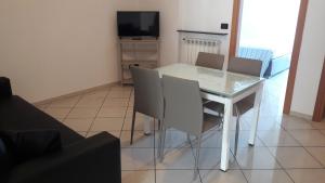 tavolo da pranzo bianco con sedie e televisore di Residenza Leonarda a Vado Ligure