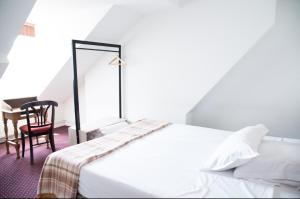 a bedroom with a white bed and a chair at Le Victor Hugo in Montrouge