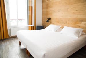 a large white bed in a room with a window at Le Victor Hugo in Montrouge