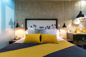 a bedroom with a large bed with two yellow pillows at Epic Boutique Hotel in Medellín