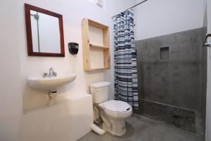 a bathroom with a toilet a sink and a mirror at Wabi Hostel in Playa del Carmen