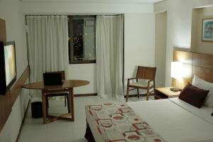 a hotel room with a bed and a table and chair at Best Hotel Sobral in Sobral