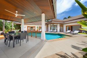 un patio al aire libre con mesa y sillas y una piscina en Mai Tai, luxury 3 bedroom villa en Choeng Mon Beach