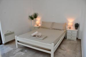 uma cama branca com duas mesas de cabeceira e dois candeeiros em Central flat, 300m from the beach em Lerápetra