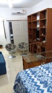 a bedroom with a bed and two chairs and a table at Bahia Flat in Salvador