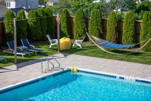 a backyard with a pool and a hammock and chairs at Aqualina Inn Montauk in Montauk