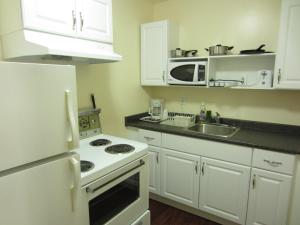 a kitchen with white appliances and a white refrigerator at Village Inn & Suites - Sudbury in Lively