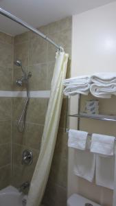 a shower with a shower curtain and towels in a bathroom at Village Inn & Suites - Sudbury in Lively