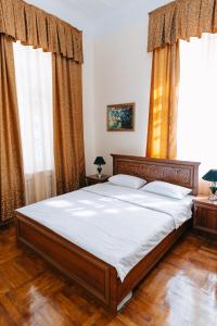 1 dormitorio con 1 cama con sábanas blancas y 2 ventanas en Lion B&B, en Samarkand