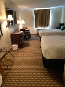 a hotel room with two beds and a desk at Rest Inn Fort Smith in Fort Smith