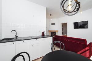 a kitchen with white cabinets and a red couch at Sopotel in Sopot