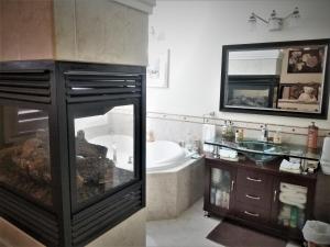 een badkamer met een bad en een grote spiegel bij Along River Ridge in Calgary